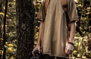 A person holding a camera in the woods.