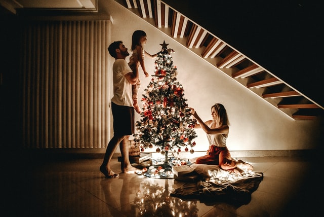 A family decorating a Christmas tree - something you will do too while decorating your house.