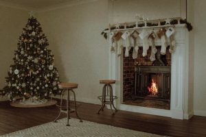 A beautifully decorated fire place and a Christmas tree next to it.