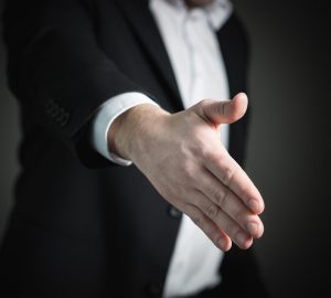 A person in a suit offering a hand for handshake.